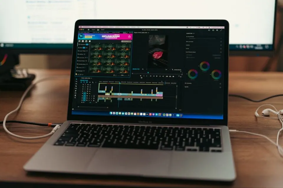 MacBook Air đặt trên bàn cạnh màn hình rời đang mở phần mềm dựng video
