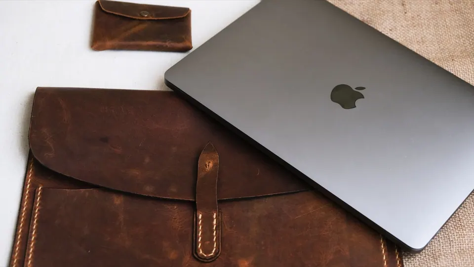Túi da đựng MacBook đặt cạnh máy