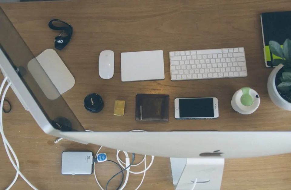Bàn làm việc nhìn từ trên xuống với iMac, bàn phím, Magic Trackpad và phụ kiện Apple